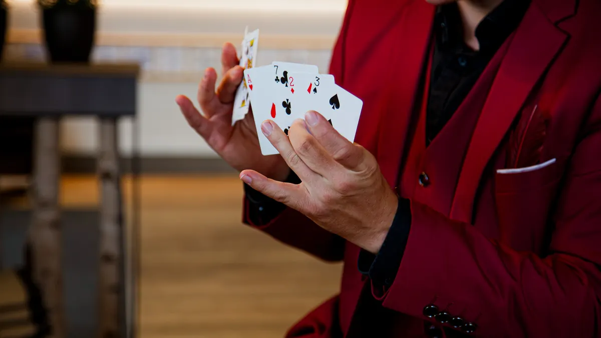 Zauberer im roten Anzug fächert Spielkarten in der Hand